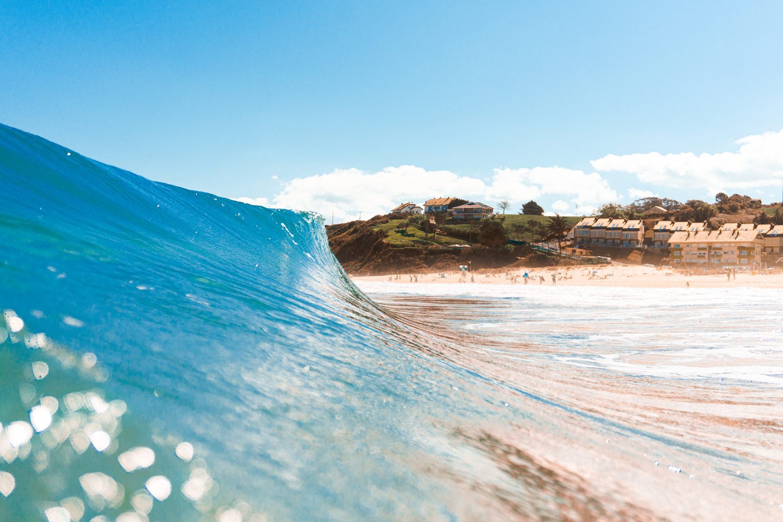 The wave curls like a gentle embrace, carrying the whole sunlit world within its glassy arms toward home.