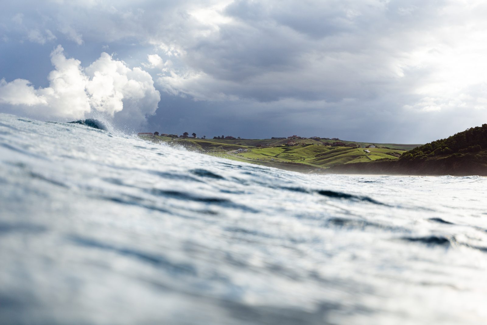 Riding the swell toward home, where green hills wait like open arms and the horizon holds every promise of return.