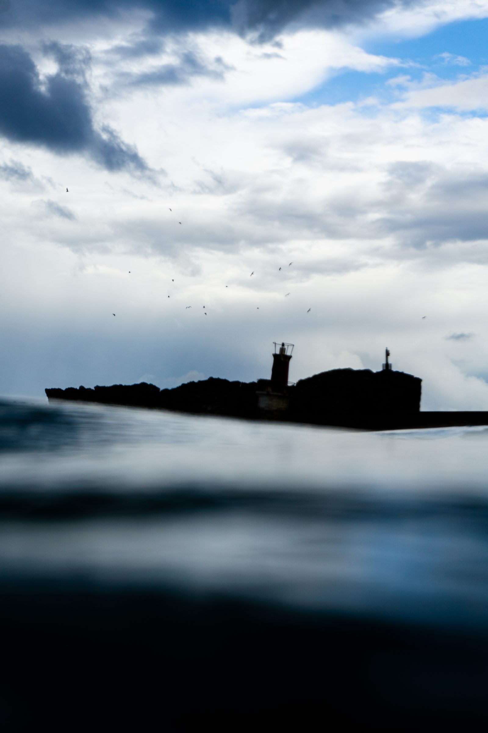 Even from the water's edge, home always waits on the horizon—a quiet beacon reminding us that love, like the shoreline, never truly disappears.
