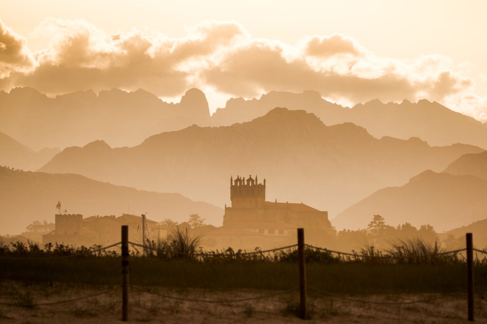 Golden light wraps the distant church and mountains alike, a gentle reminder that love, like dusk, softens every distance between hearts.