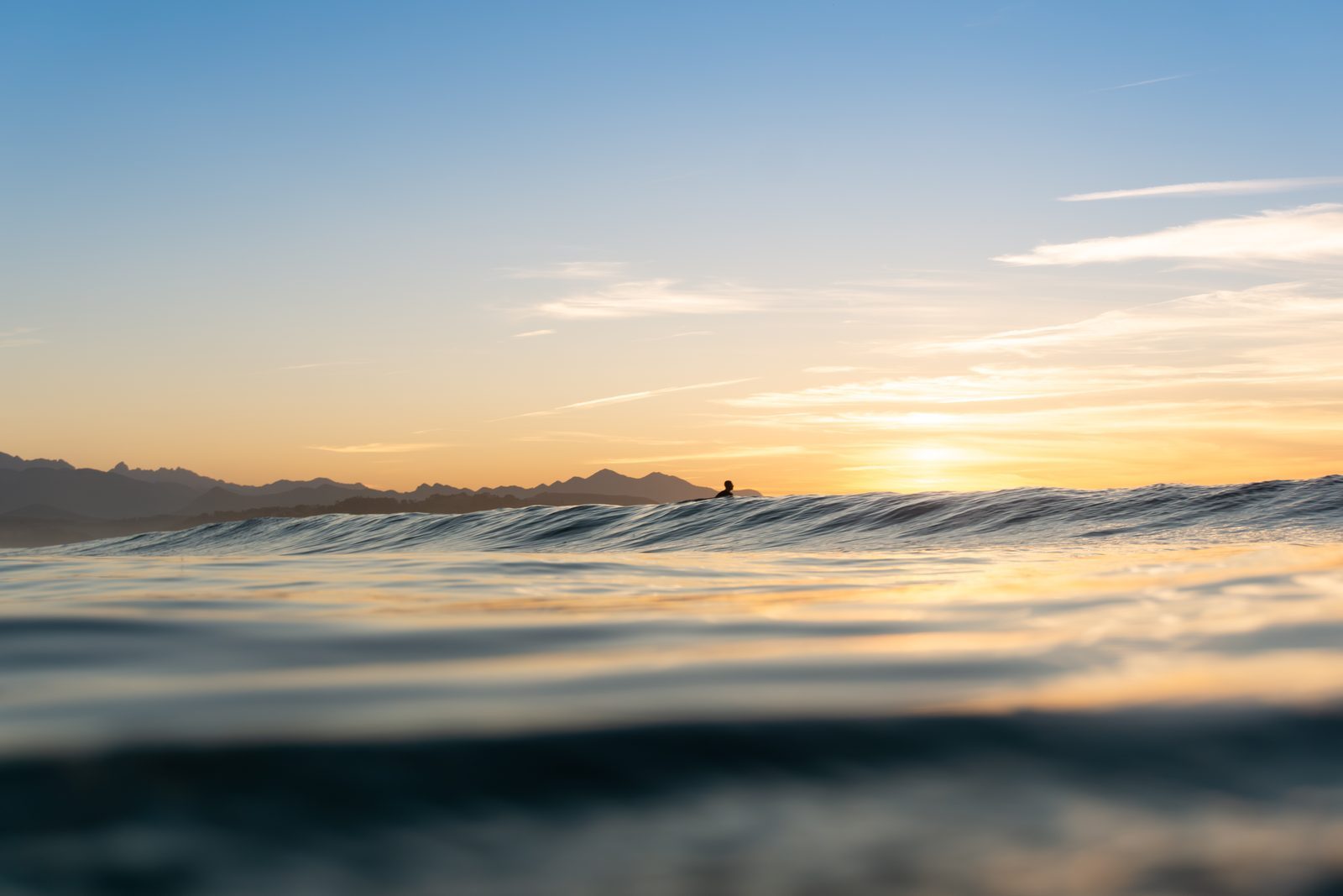In the hush between waves, a lone silhouette waits for the sun—a quiet reminder that love, too, finds us in stillness.