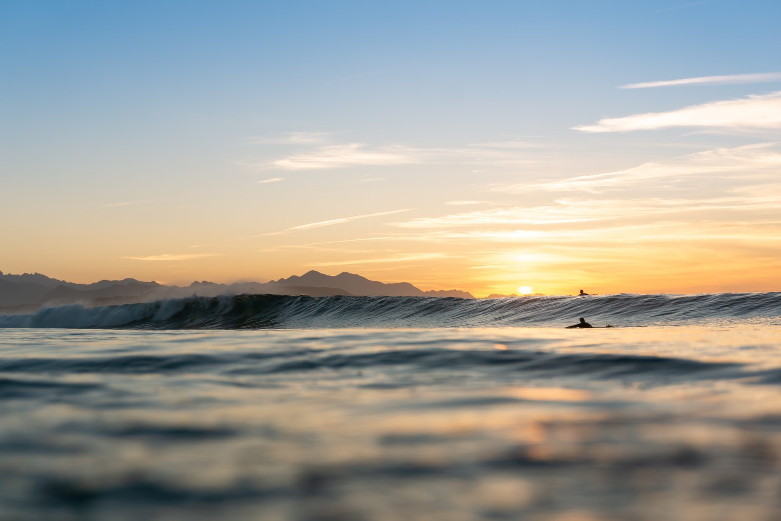 Floating quietly in the golden hush of dawn, a surfer waits for the perfect wave—a gentle reminder that love, too, asks for patience.