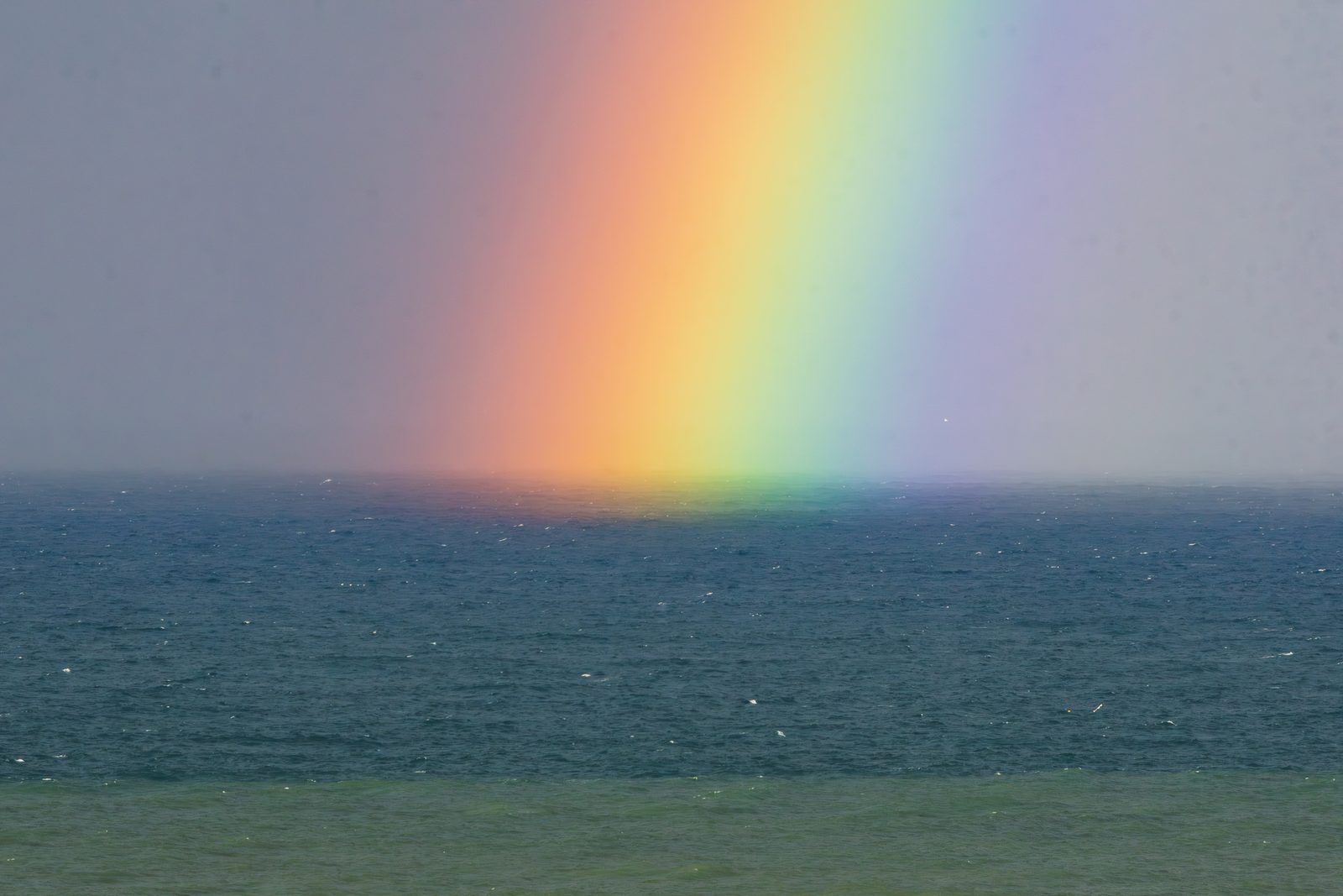 Where sea meets sky, a rainbow bridges the distance between us, reminding me that love always finds its way through the storm.